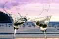 Two cocktails with splashing martini and olives on a sunset beach Royalty Free Stock Photo