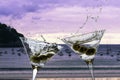 Two cocktails with splashing martini and olives on a sunset beach Royalty Free Stock Photo