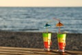 Two cocktails with straws on a wooden table top in the sun on the beach, empty space Royalty Free Stock Photo