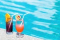 Two cocktails at swimming pool in luxurious hotel at sunny summer day. Mocktail drinks with straws at poolside in luxury Royalty Free Stock Photo