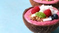Two coconut bowls with smoothies with berries and nuts in them on a blue table, AI Royalty Free Stock Photo
