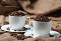 Two coffee cups with coffee beans.
