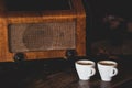 Two coffee cups with espresso and retro radio on dark wooden background. Vintage color tone Royalty Free Stock Photo