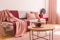 Two coffee cups on wooden coffee table next to classy grey settee with pastel pink pillows and burgundy and pastel pink blankets Royalty Free Stock Photo