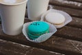 Two coffee in paper cups, two macaroons of mint and white color on a wooden vintage table. Royalty Free Stock Photo