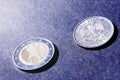 Two coins euro and ruble closeup on dark background in sunlight, heads and tails