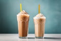 Two cold latte coffee drinks with ice cream or cream with a straw in clear glass faceted glasses on a table on a plain Royalty Free Stock Photo