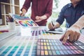 Two colleague creative graphic designer working on color selection and color swatches, drawing on graphics tablet at workplace Royalty Free Stock Photo