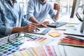 Two colleague creative graphic designer working on color selection and color swatches, drawing on graphics tablet at workplace