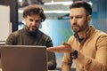 Two colleagues communicating, discussing business project, using laptop at company office Royalty Free Stock Photo