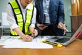 Two colleagues discussing data working and tablet, laptop with architectural project at construction site at desk Royalty Free Stock Photo