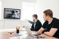 Two colleagues are sitting at table in the office. They are looking at TV-screan. They wear black clothes Royalty Free Stock Photo