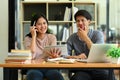 Two college students using digital tablet in library, studying together for exam or research for project Royalty Free Stock Photo