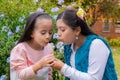 Two Colombian Latin American girls blow a dandelion in the garden of the house Royalty Free Stock Photo