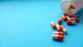 Two-color medical capsules spilled out of a bottle of medicine. Red and white pills are poured out of a jar on a blue Royalty Free Stock Photo