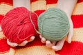 two colored skeins of wool in hands on a yellow-red knitted tablecloth Royalty Free Stock Photo