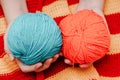 two colored skeins of wool in hands on a yellow-red knitted tablecloth Royalty Free Stock Photo