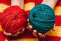 two colored skeins of wool in hands on a yellow-red knitted tablecloth Royalty Free Stock Photo