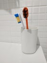 Two colored toothbrushes in white plastic glass. Royalty Free Stock Photo
