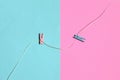 Two colored wooden pegs and small rope lie on texture background of fashion pastel blue and pink colors paper in minimal concept