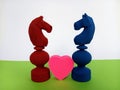 Two colorful Abstract chess pieces with a heart shape between them on a green and white background for the concept of love Royalty Free Stock Photo