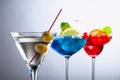 Two colorful cocktails and dry martini with green olives Royalty Free Stock Photo