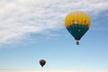 Two colorful hot air balloons float in a blue sky with wispy white clouds above Royalty Free Stock Photo