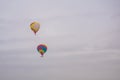 Two colorful hot air balloons flying against grey sky at aerostat festival Royalty Free Stock Photo