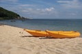 Two colorful orange kayaks on a sandy beach ready for paddlers in sunny day. Several orange recreational boats on the Royalty Free Stock Photo