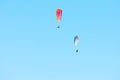 two colorful paragliders soaring through the blue sky