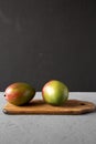 Two colorful sweet mangoes on rustic wooden board, side view. Copy space Royalty Free Stock Photo