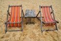 Two colorful wooden lounge chairs on sand beach Royalty Free Stock Photo