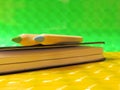 Two colour pencils and a notebook on green and yellow glossy background Royalty Free Stock Photo