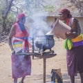 Two African tribal women cooking in cauldron