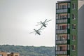 Two combat helicopters fly low over houses right in the city.