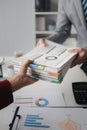 Two company employees handing over papers to each other, marketing staff handing over marketing analysis papers to department Royalty Free Stock Photo