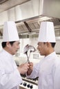 Two Competitive Chefs Face Off with Kitchen Utensils in Hands Royalty Free Stock Photo