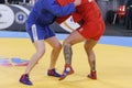 Two competitors participating in the traditional martial art of Sambo engaged in an intense match