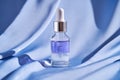 Two-component facial serum on a blue silk background.