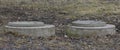 Two concrete manholes in the spring ground Royalty Free Stock Photo