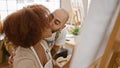 Two confident artists, partners in art and love, smiling and kissing while drawing at indoor studio class Royalty Free Stock Photo