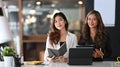 Two businesswomen sitting together in office and smiling to camera. Royalty Free Stock Photo