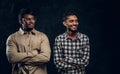 Two confident smiling Indian wearing casual clothes posing with crossed arms and looking sideways.