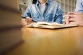 Two confident students reading a book or doing homework together while sitting at home or classroom