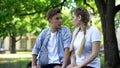 Two conflicting teenagers looking at each other, sitting on park bench, crisis Royalty Free Stock Photo