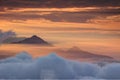 Two conical peaks above translucent autumn morning orange mist