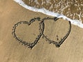 Two connected Hearts drawn on the beach sand with sea waves Royalty Free Stock Photo