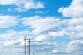 Two construction cranes against the blue cloudy sky. Tower crane for lifting loads in the construction of buildings. Royalty Free Stock Photo