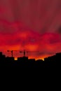 Two construction cranes over standing houses against a sunset bright sky Royalty Free Stock Photo