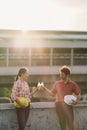 Two construction engineers celebrate after work or project at construction site or factory, man and woman bumping water bottles